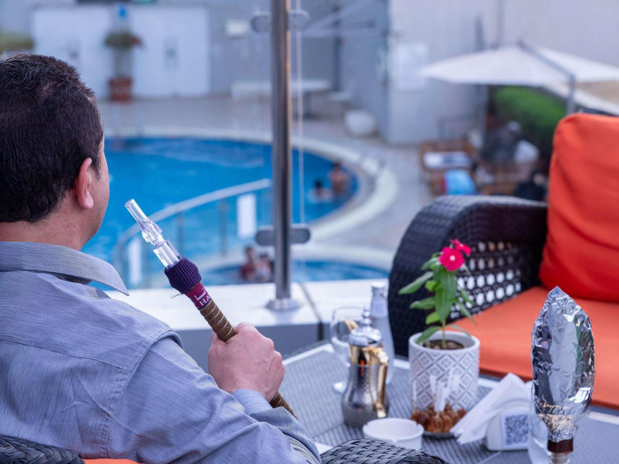 Novotel Jazan Exterior foto A man smokes a hookah in Cairo, Egypt